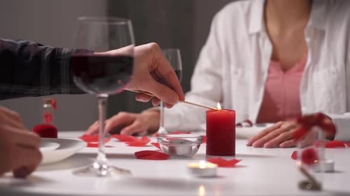 The Lovers Sit At The Table. A Man's Hand Lights A Candle For A Romantic Dinner For Valentine's Day