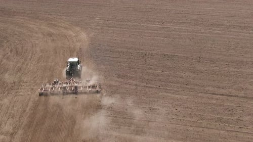 Aerial Top View of Tractor Cutting Furrows in Farm Field for Sowing Farm Tractor with Rotary Harrow