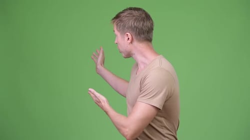 Young Handsome Scandinavian Man Presenting Something Against Green Background