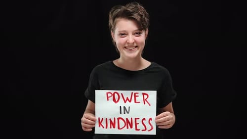 Smiling Woman Holding Power in Kindness Sign