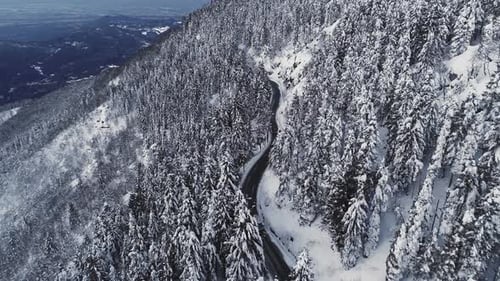 Luftaufnahme eines Autos, das in einer Wüstenstraße entlang verschneiten Bergseite fährt