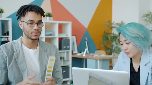 African American Young Man and Asian Girl Creative Designers Talking in Office
