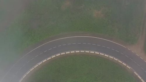 Flying Through the Clouds Over a Mountain Road Surrounded By Green Vegetation