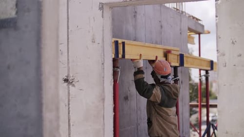 ein Arbeiter mit einem Helm installiert einen Balken auf einer Baustelle