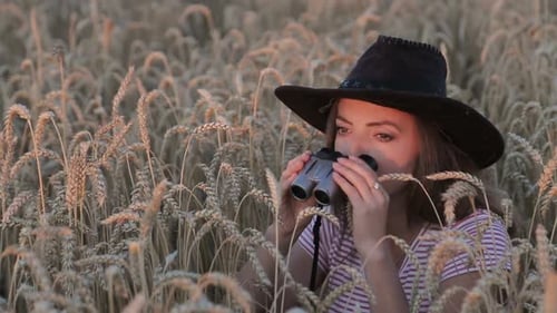 Beautiful Young Girl Looking Through Binoculars On Blue Sky Background.
