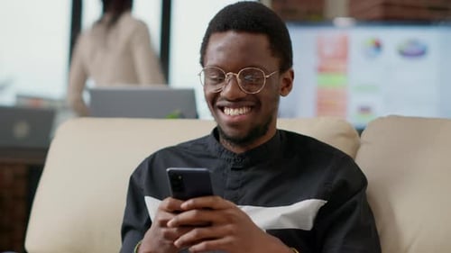Smiling Man Using Mobile Phone in Modern Office