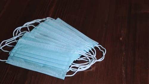 Pile of Blue Surgical Masks on Dark Wood