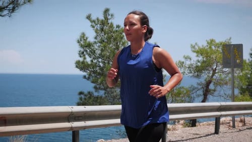 Portrait of smiling happy woman running outdoor on road along seashore.