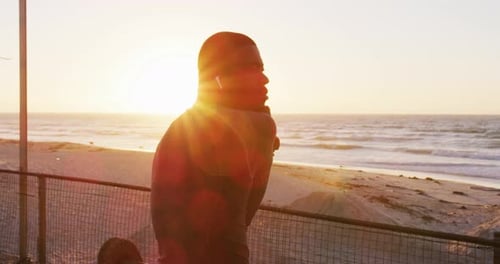 Muscular Man Stretching on Beach at Golden Hour