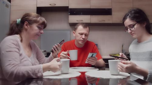 Family Using Smartphones at Kitchen Table