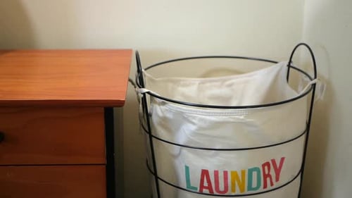 Cloths being tossed into a laundry hamper. SLOW MOTION.