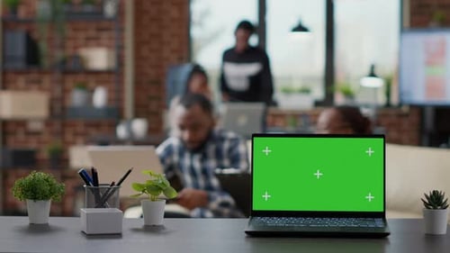 Office Desk with Green Screen on Laptop Computer in Workplace