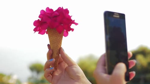 Woman Takes Picture of Flowers in Cone