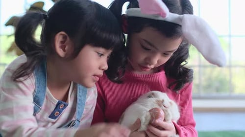 Two Children Cuddle a White Rabbit With Easter Egg