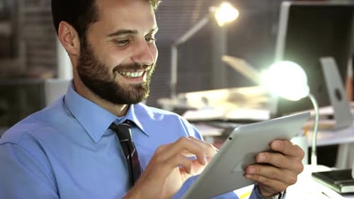 Man Using Tablet in Office at Night