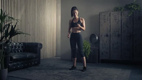 Woman Looks at Phone in Indoor Workout Space