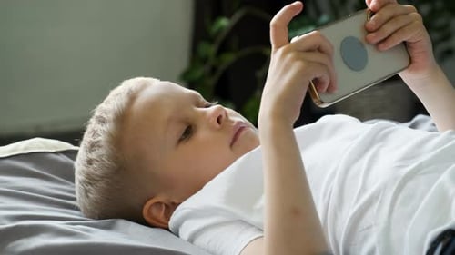 Close-up Portrait of A Child Boy Looking at the Phone Screen Playing a Game on A Smartphone