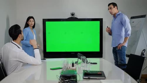 Confident Millennial Multiethnic Colleagues Discussing Project in Office with Green Screen Monitor
