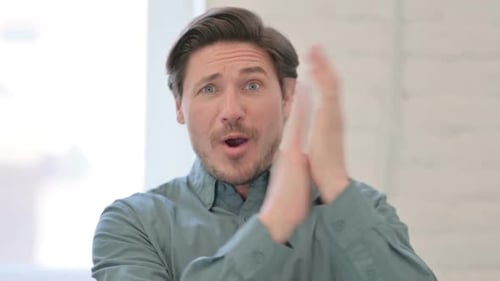 Mature Man Clapping Hands in Approval Indoors