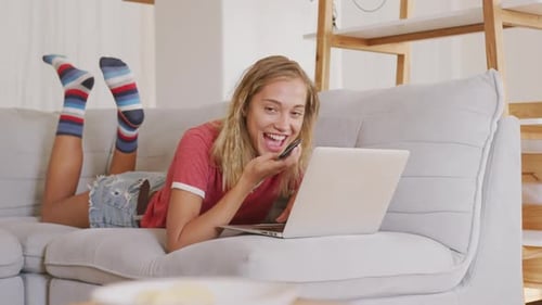 Young Woman Talking on Phone with Laptop on Couch