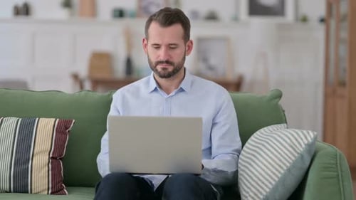 Man Typing on Laptop on Couch at Home