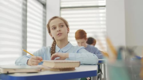 Focused Student Writing at Her Desk in Classroom
