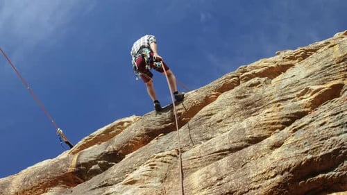 Mountaineer rappelling down the hill with the help of rope 4k