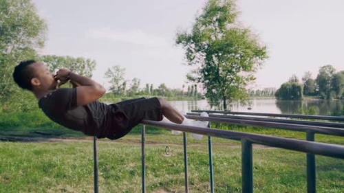 Focused Man Exercising Abs on Parallel Bars in Park
