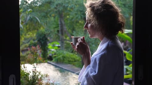 Woman in Bathrobe Enjoying Coffee in Tropical Garden