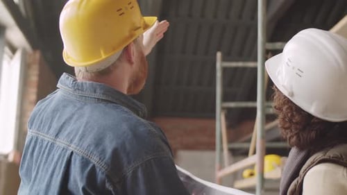 Male and Female Engineers Speaking at Construction Site
