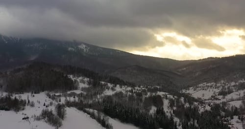 Aerial View of Mountains and Forest Covered with Snow at Sunset in Winter