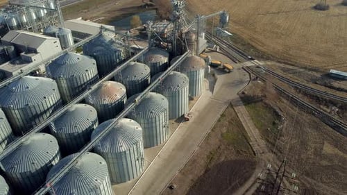 Ein Lastwagen voller Getreide fährt an einem sonnigen Tag in der Nähe großer Metallsilos des Getreideaufzugs
