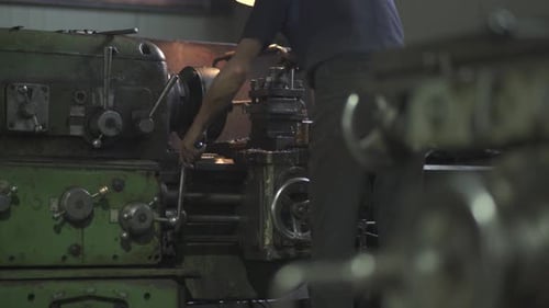 Man Operating Complex Machinery in Dark Workshop