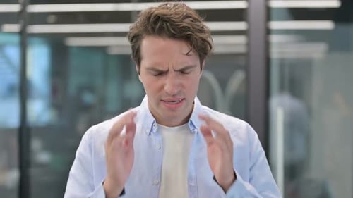 Man With Headache in Office Rubs Temples