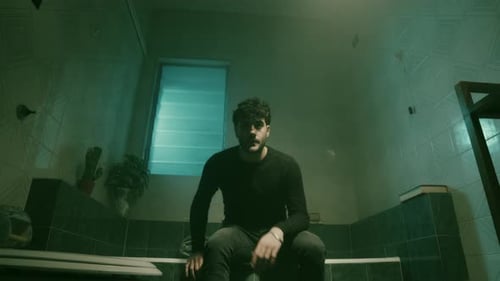 Man Sitting on Bathtub Edge Looking Sad