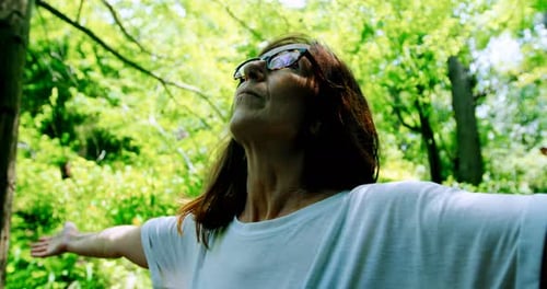 Mature woman standing with arms outstretched in the garden 4k