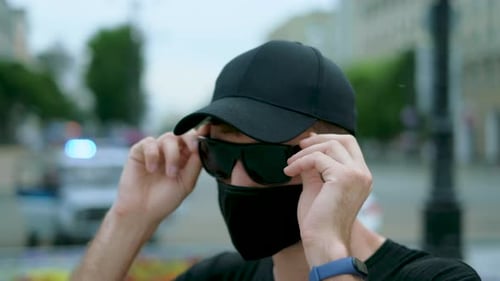 Provocateur masculin de l'Agence du FBI en coronavirus, masque facial noir, lunettes et casquette.
