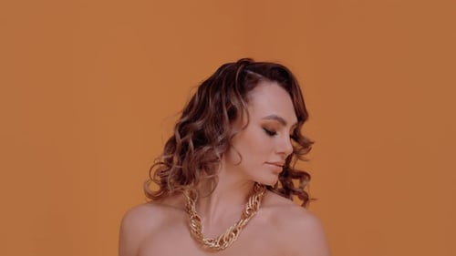 Glamorous Woman with Wavy Hair and Gold Necklace