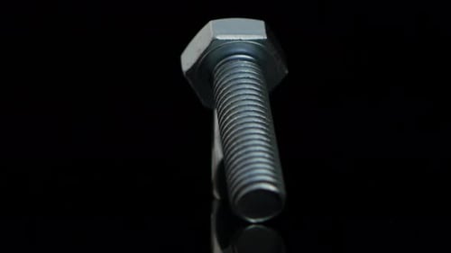 Shiny Silver Bolt and Nut on Black Surface