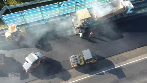 Paver lays asphalt, Road rollers drive on a new road. Roadway repair. Asphalt laying.