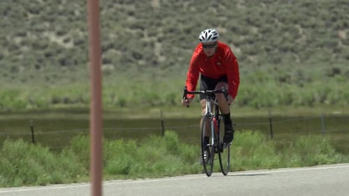 A man road biking on a scenic road.