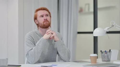 Pensive Young Redhead Man Thinking at Work