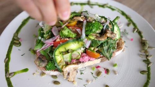 Top View of Hand Squeezing Limes Juice on Vegan Toast with Different Vegetables on Top of It