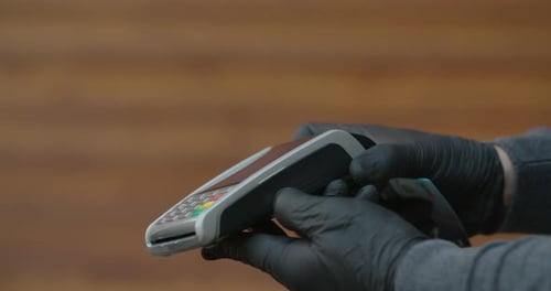 Hands Wearing Gloves Use Credit Card Terminal