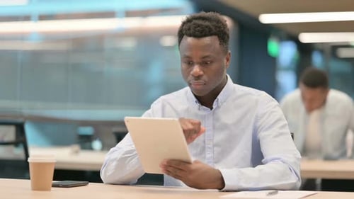 Attractive African Businessman Using Tablet in Office