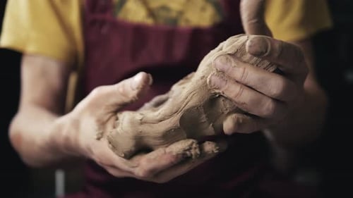 Ernsthafte Frau, die bei Pottery Wheel im Studio arbeitet, bereitet Ton vor, um den Teller