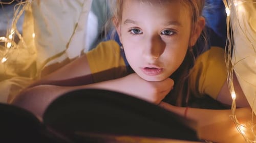 Girl Reading in a Blanket Fort at Night