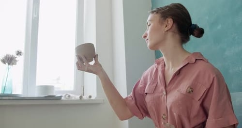 Young Woman Inspects Clay Pot in Studio