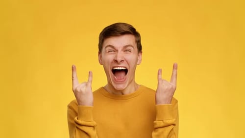 Emotional Guy Showing Rock Gesture Shouting On Yellow Background