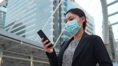 business woman using smartphone and wearing medical mask for protection from coronavirus pandemic